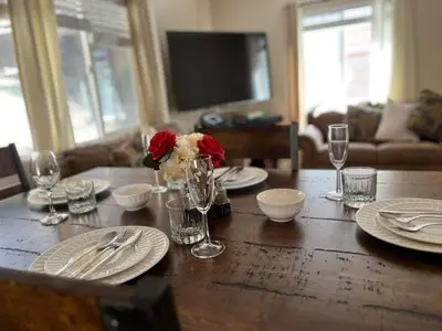 a wooden table with plates and a vase of flowers on it at Cozy Cabin in Crestline