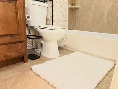 a bathroom with a toilet and a white rug at Cozy Cabin in Crestline