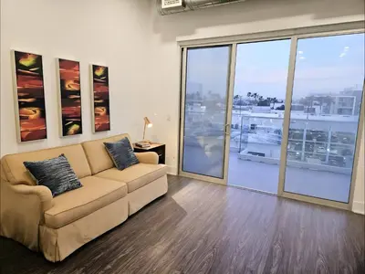 a living room with a couch and large windows at Venice Beach Getaway Steps from the Ocean Marina and Boardwalk in Los Angeles