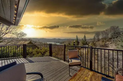 a deck with a chair and a view of the mountains at Koda House in Lake Arrowhead