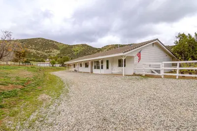 a white building with a flag on the side of it at Patio, Fire Pit and Hillside Views Agua Dulce Home in Leona Valley
