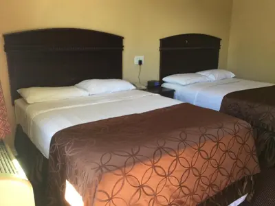 a hotel room with two beds with white and brown covers at Carlton Motor Lodge in Los Angeles
