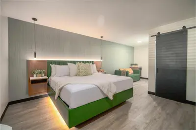 a bedroom with a large bed with a green headboard at LYFE INN & SUITES by AGA- North Hollywood Near Universal Studios in North Hollywood