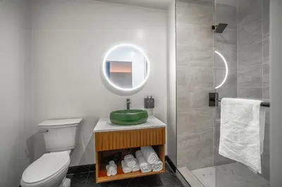 a bathroom with a toilet and a round mirror at LYFE INN & SUITES by AGA- North Hollywood Near Universal Studios in North Hollywood