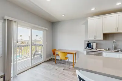 a kitchen with a table and chairs and a balcony at Seaspray at Anacapa View in Port Hueneme