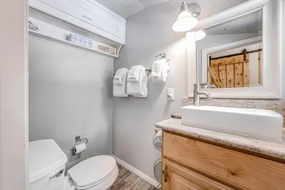 a bathroom with a toilet and a sink and a mirror at Castle Rock Cabin #1 ~ Comfortable cabin with modern amenities and deck - near hiking and lake in Big Bear Lake