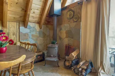 a dining room with a wood stove in a cabin at Castle Rock Cabin #2 ~ Cozy cabin close to Fisher Cove & Boulder Bay - short drive to skiing in Big Bear Lake