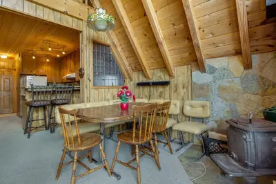 a dining room with a table and chairs and a stove at Castle Rock Cabin #2 ~ Cozy cabin close to Fisher Cove & Boulder Bay - short drive to skiing in Big Bear Lake