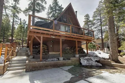 a house with a wrap around deck in the woods at Castle Rock Cabin #2 ~ Cozy cabin close to Fisher Cove & Boulder Bay - short drive to skiing in Big Bear Lake