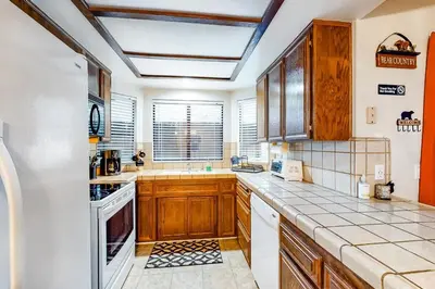 a large kitchen with wooden cabinets and white appliances at Rosie's Hideaway ~ Spacious Retreat Near the Mountain & Lake with Grill & Full Kitchen in Big Bear Lake