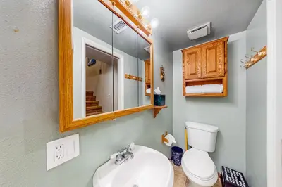 a bathroom with a sink and a mirror and a toilet at Rosie's Hideaway ~ Spacious Retreat Near the Mountain & Lake with Grill & Full Kitchen in Big Bear Lake