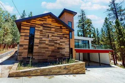 a small house with a brick wall at Hillside Hideaway ~ Dog-friendly home with wraparound deck, grill, game room, & bar - walk to dining in Big Bear Lake