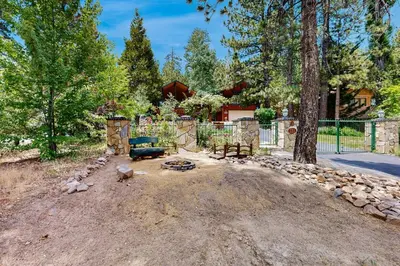 a backyard with a fire pit and a tree at Rooster's Den ~ Charming house with expansive deck, cable, internet, near Big Bear Lake in Big Bear Lake
