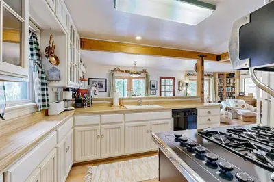 a kitchen with white cabinets and a stove top oven at Rooster's Den ~ Charming house with expansive deck, cable, internet, near Big Bear Lake in Big Bear Lake