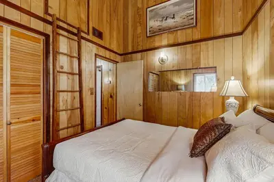 a bedroom with a bed and wood paneled walls at Idle Ours Cabin ~ Rustic and Cozy Cabin with Fireplace & Private BBQ - Walk to Big Bear Lake in Fawnskin