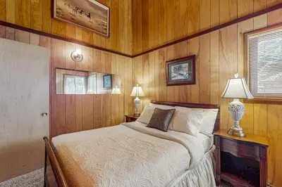 a bedroom with a bed in a wooden wall at Idle Ours Cabin ~ Rustic and Cozy Cabin with Fireplace & Private BBQ - Walk to Big Bear Lake in Fawnskin