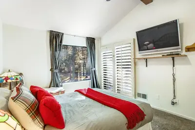 a bedroom with a bed with red pillows and a flat screen tv at Summit Hideaway ~ Fantastic Mountain getaway with private hot tub, free Wi-Fi, full kitchen, & more in Big Bear Lake