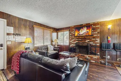 a living room with a leather couch and a fireplace at Meadow-Front Metcalf Bay Cabin Hot Tub, Air Hockey, Firepit & Lake Views in Big Bear Lake