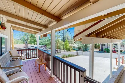 a porch of a home with chairs and a table at Lazy Bear Cabin ~ Dog-friendly home with private hot tub, ping-pong, basketball & firepit in Big Bear Lake