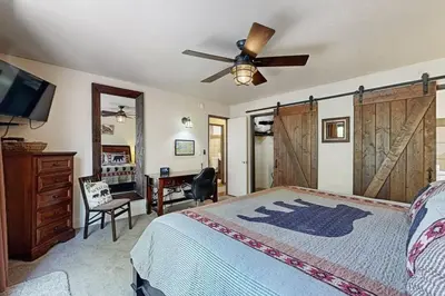 a bedroom with a bed with a ceiling fan and a desk at Lazy Bear Cabin ~ Dog-friendly home with private hot tub, ping-pong, basketball & firepit in Big Bear Lake