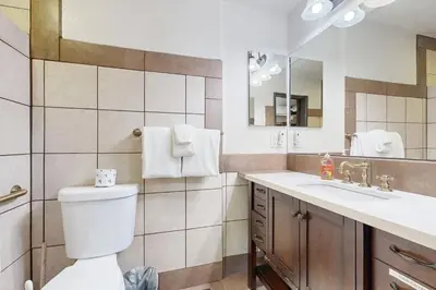 a bathroom with a toilet and a sink and a mirror at Lazy Bear Cabin ~ Dog-friendly home with private hot tub, ping-pong, basketball & firepit in Big Bear Lake
