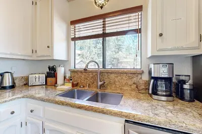a kitchen counter with a sink and a window at Lazy Bear Cabin ~ Dog-friendly home with private hot tub, ping-pong, basketball & firepit in Big Bear Lake