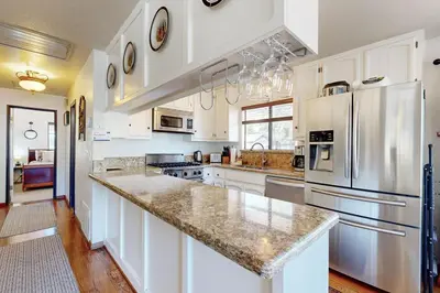 a kitchen with white cabinets and stainless steel appliances at Lazy Bear Cabin ~ Dog-friendly home with private hot tub, ping-pong, basketball & firepit in Big Bear Lake