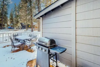 a grill on the side of a house with a table at Moose-in' Around ~ Walk to Slopes Mountain Home with Private Hot Tub, Ski Locker & Playground in Big Bear Lake