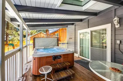 a jacuzzi tub on a porch with a table at Moose-in' Around ~ Walk to Slopes Mountain Home with Private Hot Tub, Ski Locker & Playground in Big Bear Lake