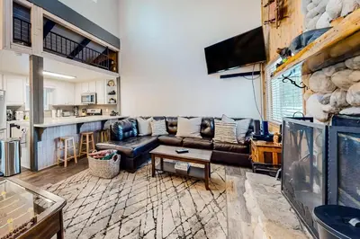 a living room with a leather couch and a bar at Moose-in' Around ~ Walk to Slopes Mountain Home with Private Hot Tub, Ski Locker & Playground in Big Bear Lake