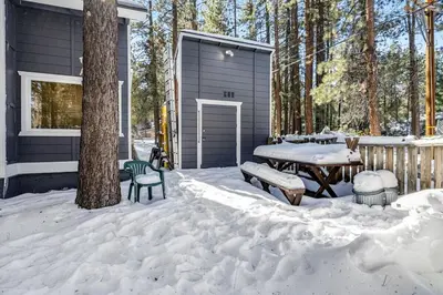 a house with a picnic table in the snow at Moose-in' Around ~ Walk to Slopes Mountain Home with Private Hot Tub, Ski Locker & Playground in Big Bear Lake