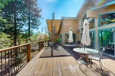 a wooden deck with a table and umbrella at Big Bear 7th Heaven ~ Lakeview Chalet with Hot Tub, Sauna, Grill, Great Deck Views in Fawnskin