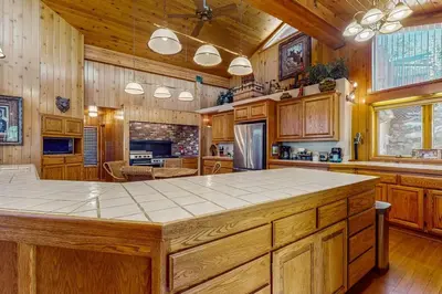 a large kitchen with wooden cabinets and a large island at Big Bear 7th Heaven ~ Lakeview Chalet with Hot Tub, Sauna, Grill, Great Deck Views in Fawnskin