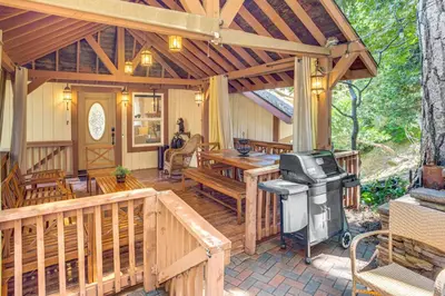 a large wooden porch with a grill and a stove at Forest Views and Fire Pit! Cozy Cabin in Crestline in Crestline