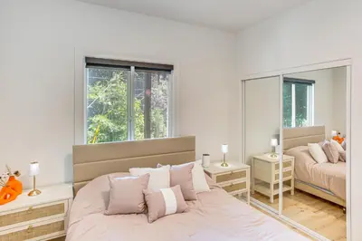 a white bedroom with a bed and a mirror at Forest Views and Fire Pit! Cozy Cabin in Crestline in Crestline