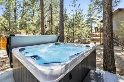 a jacuzzi tub sitting on a patio with trees at The Fox Den Big Bear ~ Modern Mountain View Retreat w/ Hot Tub in Big Bear City
