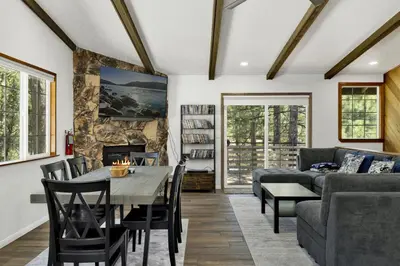 a living room with a table and a couch at The Fox Den Big Bear ~ Modern Mountain View Retreat w/ Hot Tub in Big Bear City