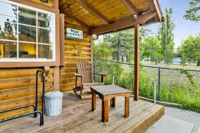 a cabin with a table and a chair on a porch at Orchard Family Cabin Near Historic Big Bear Village Walk to Marina in Big Bear Lake