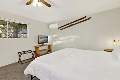 a white bedroom with a bed and a television at Orchard Family Cabin Near Historic Big Bear Village Walk to Marina in Big Bear Lake