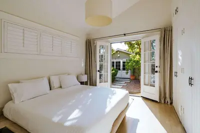 a bedroom with a large white bed and an open door at Venice 2BR and Guest Studio with Tub & Garden in Los Angeles