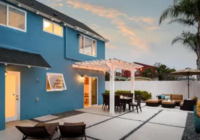 a blue house with a patio with a table and chairs at Sea La Vie by Paradise Retreats in Ventura