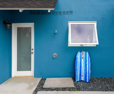 a blue wall with a surfboard next to a door at Sea La Vie by Paradise Retreats in Ventura