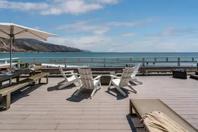 a patio with chairs and an umbrella and the ocean at The Cove at Rincon by Paradise Retreats in Carpinteria