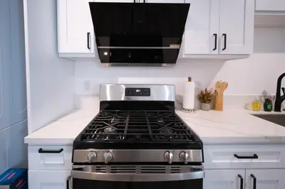 a stove top oven in a kitchen with white cabinets at Modern 2BR2BA Home Near USC Walk to Campus in Los Angeles