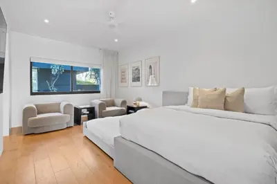 a white bedroom with a large bed and chairs at Surfside Malibu by Stay Awhile Villas in Malibu