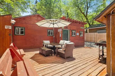 a wooden deck with a table and an umbrella at Lily's Bear Cabin #2544 in Big Bear Lake