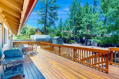 a wooden deck with a grill and chairs on it at Lazy Bear Cabin #554 in Big Bear Lake