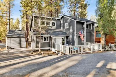 a gray house with a porch and an american flag at Moose-in' Around in Big Bear Lake