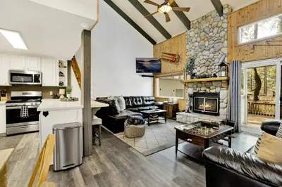 a kitchen and living room with a stone fireplace at Moose-in' Around in Big Bear Lake