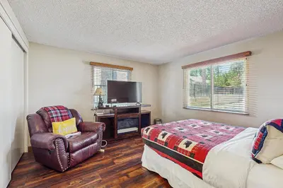 a bedroom with a bed and a chair and a tv at Meadow-Front Metcalf Bay Gem #542 in Big Bear Lake